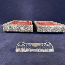 12 geslepen kristallen messenleggers in 2 kartonnen doosjes. Formaat van het doosje 14 x 9,5 cm.